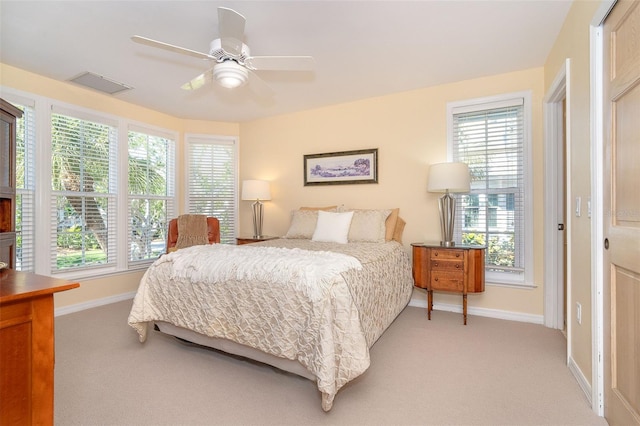 bedroom featuring light carpet, multiple windows, visible vents, and baseboards