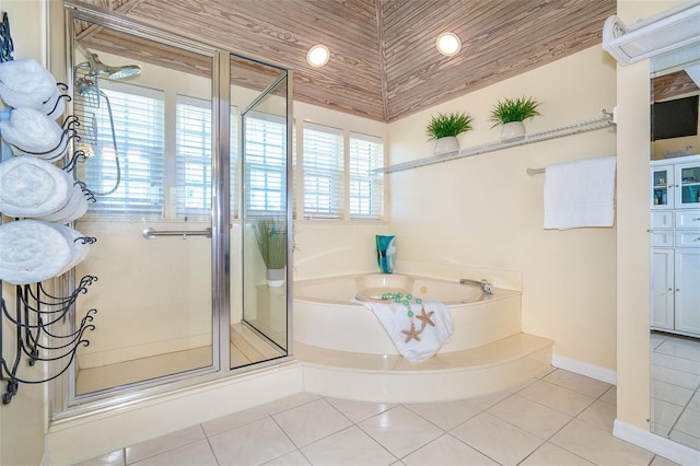 bathroom with a garden tub, a shower stall, baseboards, and tile patterned floors