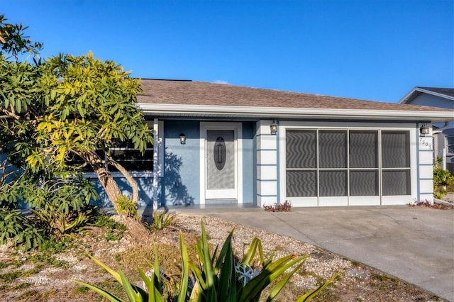 view of front of home with stucco siding, driveway, and roof with shingles