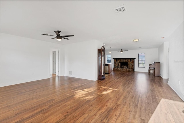 unfurnished living room featuring visible vents, a fireplace, a ceiling fan, and wood finished floors