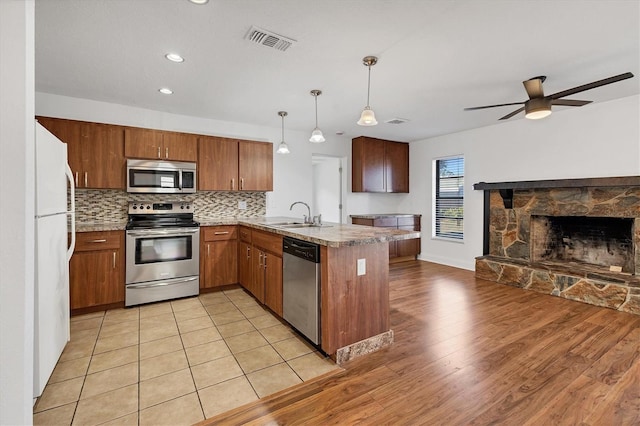 kitchen featuring visible vents, a sink, backsplash, appliances with stainless steel finishes, and a peninsula