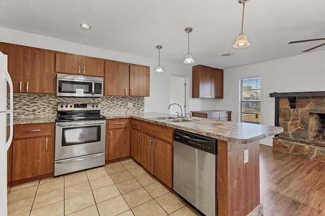 kitchen featuring visible vents, backsplash, a peninsula, stainless steel appliances, and a sink