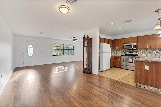 kitchen with stainless steel appliances, visible vents, ceiling fan, and brown cabinetry