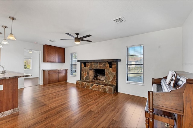 living room featuring a wealth of natural light, visible vents, dark wood finished floors, and a ceiling fan