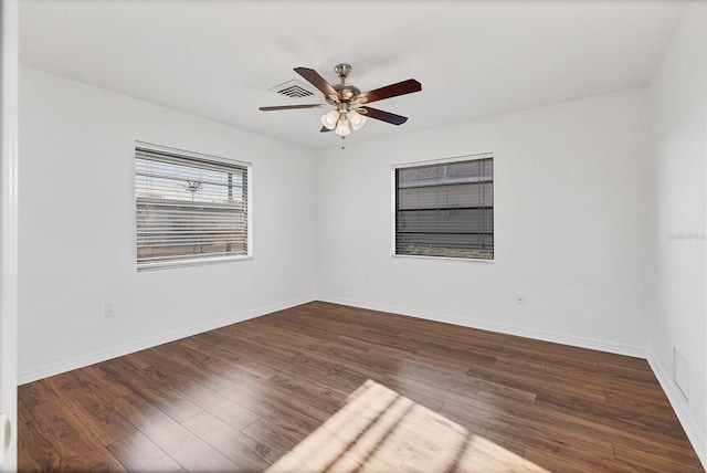 spare room featuring visible vents, a ceiling fan, baseboards, and wood finished floors