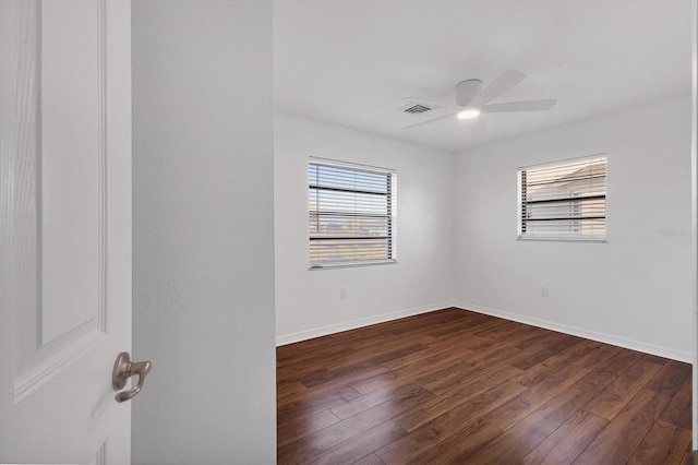 empty room with dark wood-style floors, visible vents, baseboards, and a ceiling fan