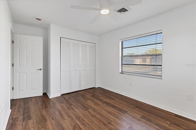 unfurnished bedroom with a ceiling fan, baseboards, visible vents, dark wood-style flooring, and a closet