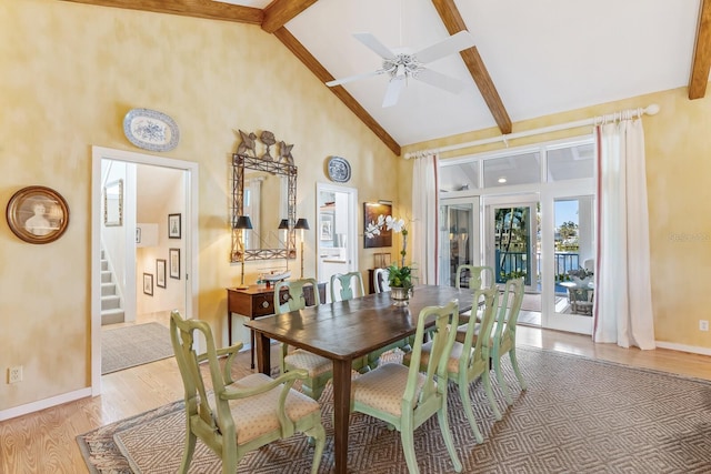 dining room with high vaulted ceiling, light wood-type flooring, beamed ceiling, and stairway