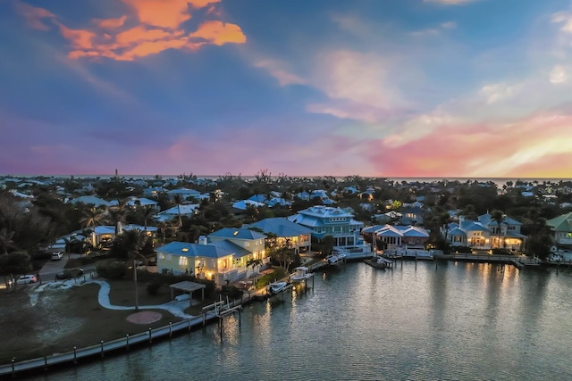 aerial view at dusk with a water view and a residential view