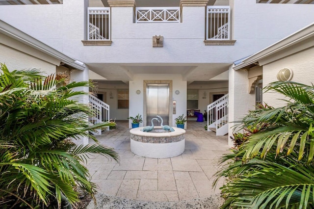 doorway to property with elevator, a patio area, and stucco siding