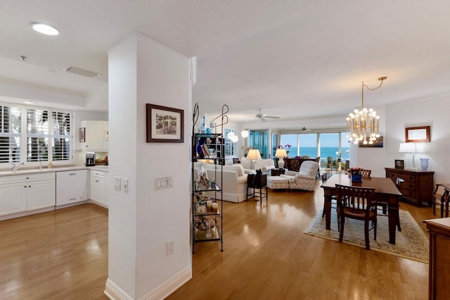 dining space featuring light wood-style floors, baseboards, and ceiling fan with notable chandelier