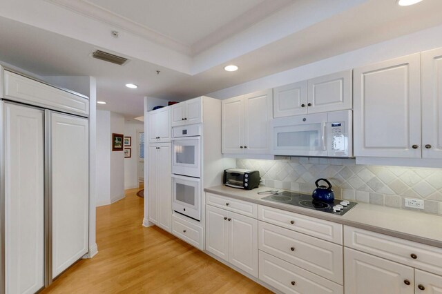 kitchen with white appliances, visible vents, decorative backsplash, light wood-style flooring, and light countertops