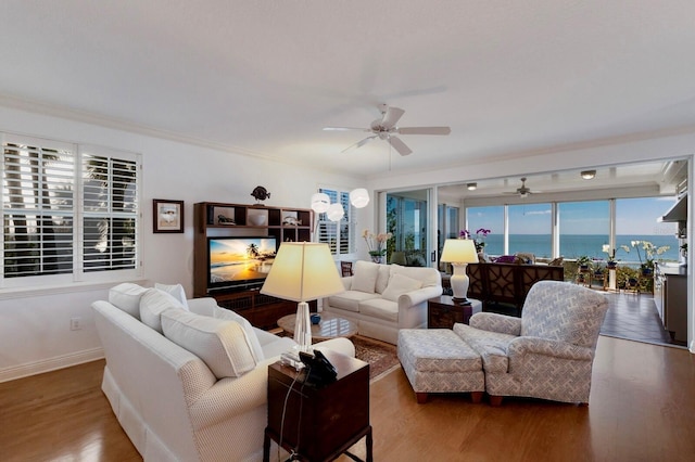 living room featuring ceiling fan, baseboards, wood finished floors, and ornamental molding