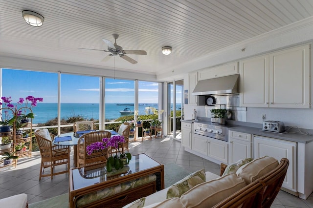 living area with ceiling fan, a water view, and light tile patterned flooring