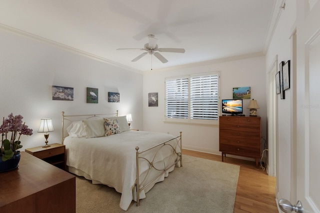 bedroom with ceiling fan, light wood-type flooring, baseboards, and crown molding