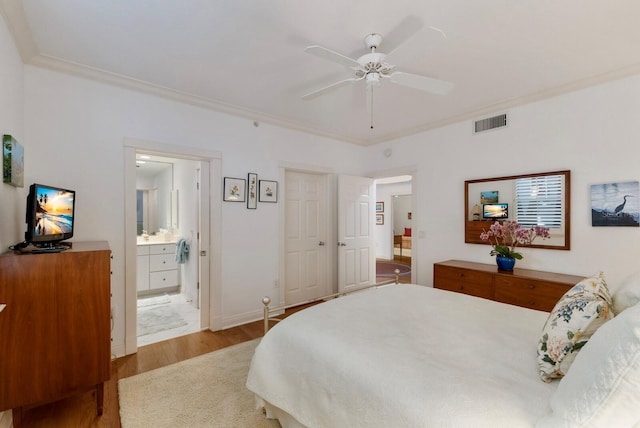 bedroom with baseboards, visible vents, ornamental molding, wood finished floors, and ensuite bathroom