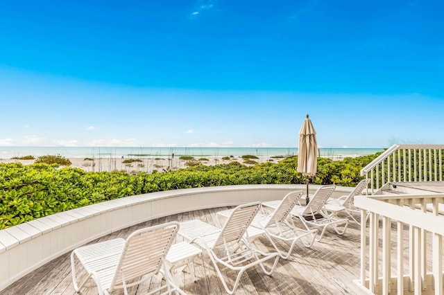 view of property's community featuring a view of the beach and a deck with water view