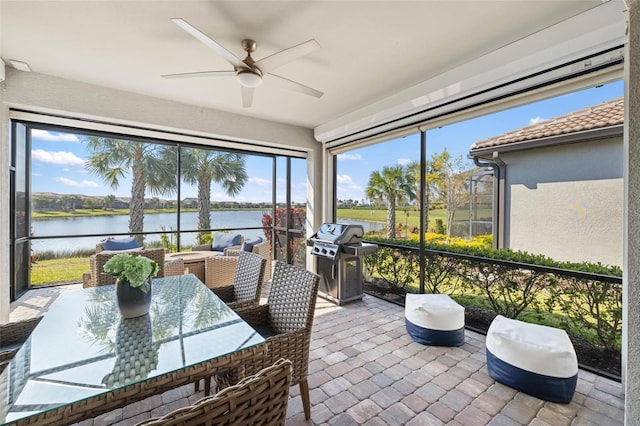 sunroom / solarium with a ceiling fan and a water view