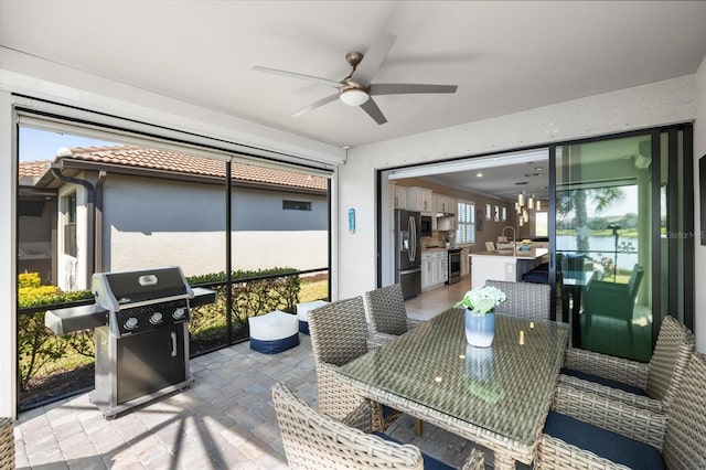 sunroom / solarium with ceiling fan, plenty of natural light, and a sink