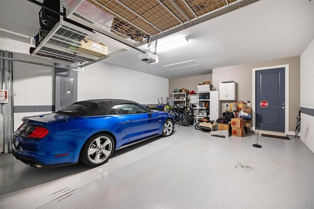 garage with a garage door opener, concrete block wall, and electric panel