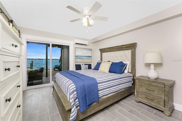 bedroom featuring access to exterior, a wall unit AC, a water view, wood tiled floor, and ceiling fan