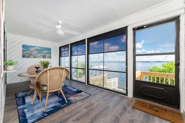 sunroom / solarium featuring a water view and a ceiling fan