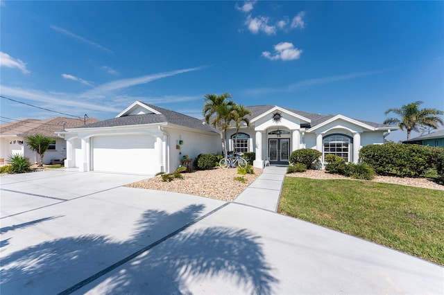 view of front of house with concrete driveway, an attached garage, french doors, a front yard, and stucco siding