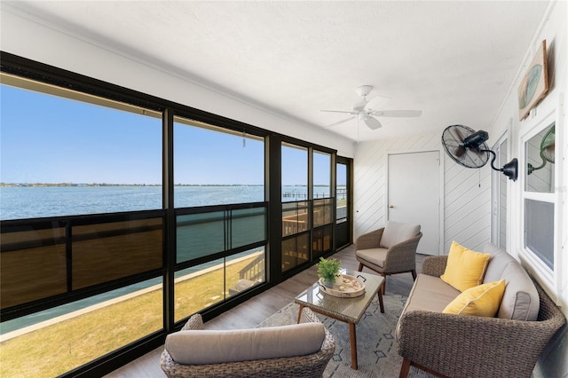 sunroom featuring a ceiling fan and a water view