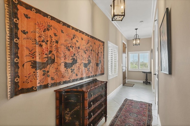 corridor featuring a chandelier, tile patterned flooring, crown molding, and baseboards