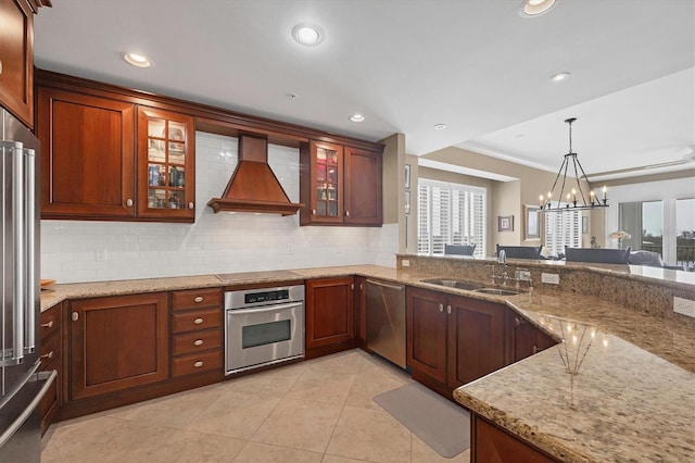 kitchen with decorative backsplash, appliances with stainless steel finishes, decorative light fixtures, custom exhaust hood, and a sink