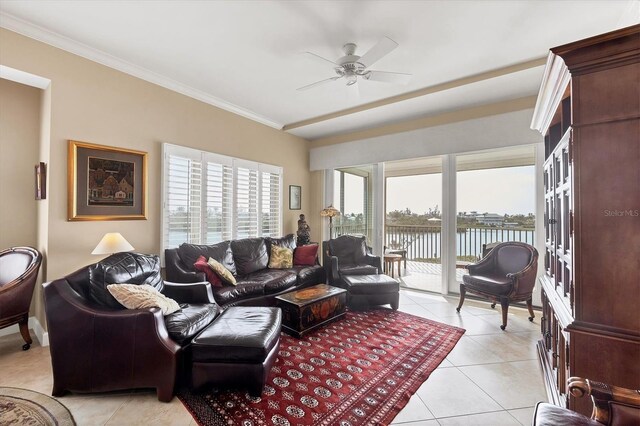 living area with ornamental molding, light tile patterned flooring, a ceiling fan, and a water view