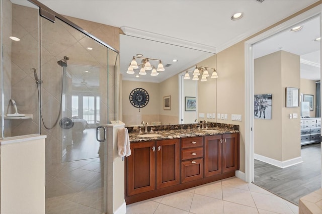 full bathroom featuring double vanity, a stall shower, a sink, and crown molding