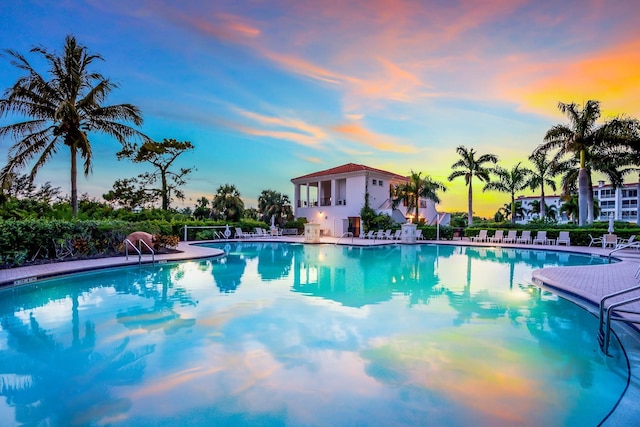 pool at dusk with a patio and a community pool