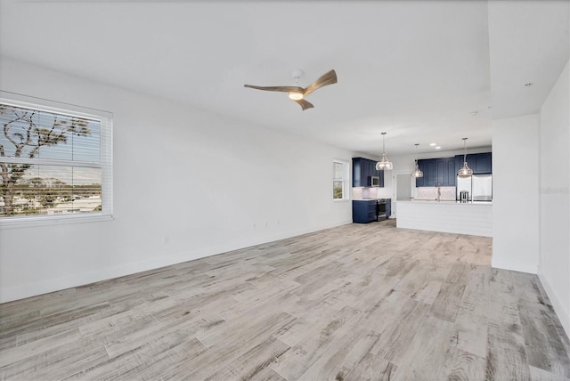 unfurnished living room featuring ceiling fan, light wood finished floors, and baseboards