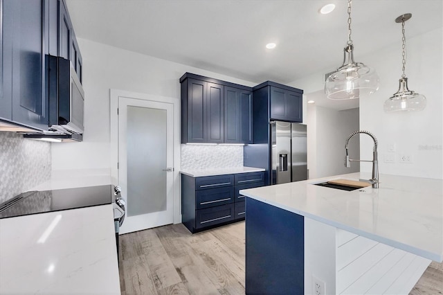 kitchen with blue cabinets, stainless steel appliances, light wood-type flooring, pendant lighting, and a sink