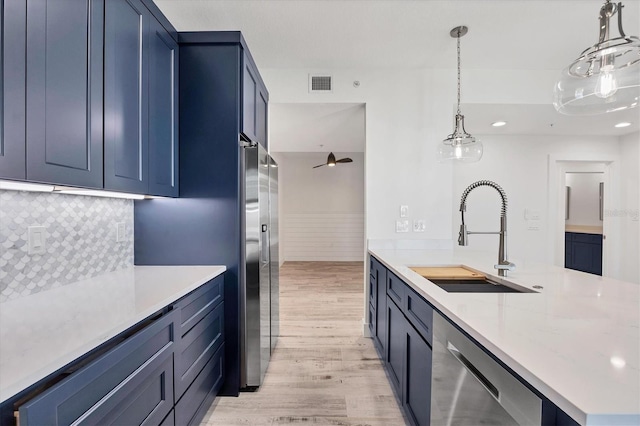 kitchen featuring stainless steel appliances, a sink, visible vents, decorative backsplash, and light wood finished floors