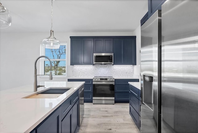 kitchen featuring tasteful backsplash, appliances with stainless steel finishes, blue cabinets, light countertops, and a sink