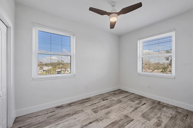 empty room featuring ceiling fan, light wood-style flooring, and baseboards