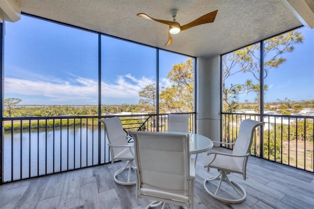 unfurnished sunroom featuring a water view and ceiling fan