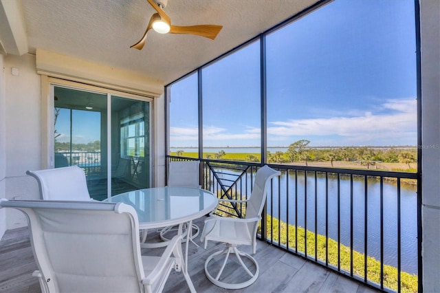 sunroom / solarium featuring a water view and ceiling fan