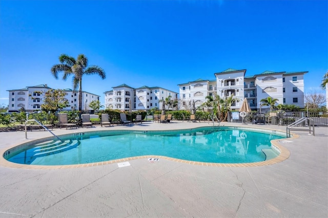 community pool with a patio area and fence