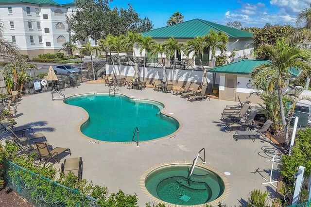 pool with a community hot tub, a patio, and fence