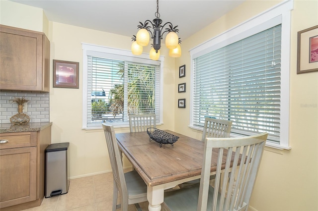 dining space with baseboards, light tile patterned floors, and an inviting chandelier