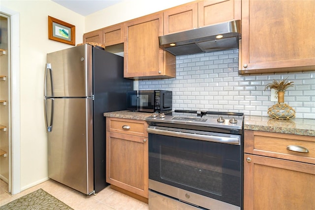 kitchen featuring under cabinet range hood, tasteful backsplash, light tile patterned floors, and appliances with stainless steel finishes