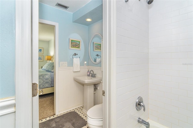 full bath featuring shower / bathtub combination, visible vents, ensuite bathroom, wainscoting, and a sink