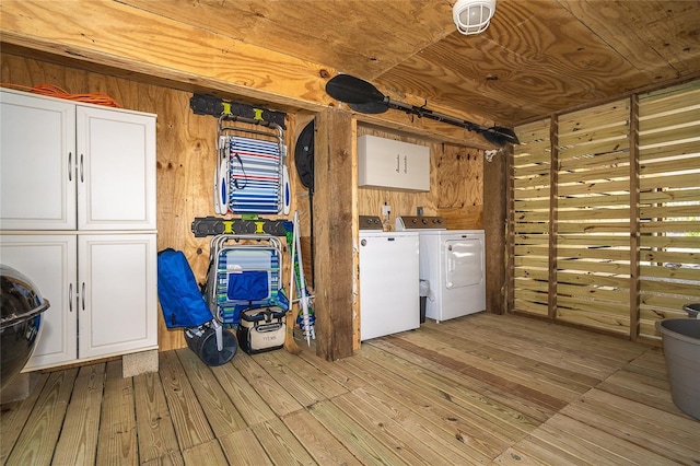 laundry room with cabinet space, wooden walls, washer and clothes dryer, wood ceiling, and wood-type flooring