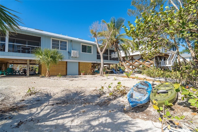 back of property featuring a sunroom, an AC wall unit, and stairs