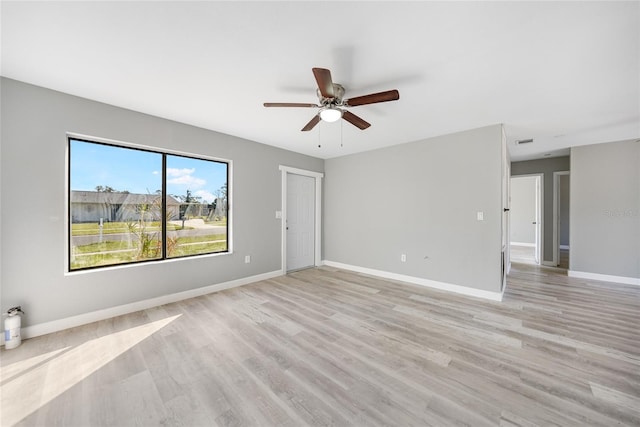 empty room featuring light wood-style floors, ceiling fan, visible vents, and baseboards