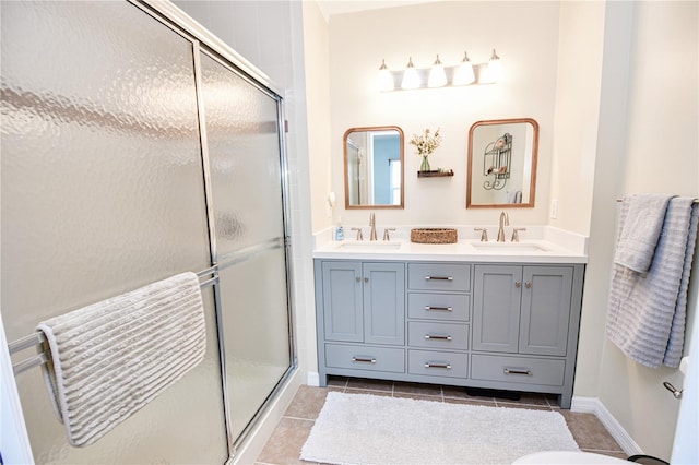 full bathroom with double vanity, a stall shower, tile patterned flooring, and a sink