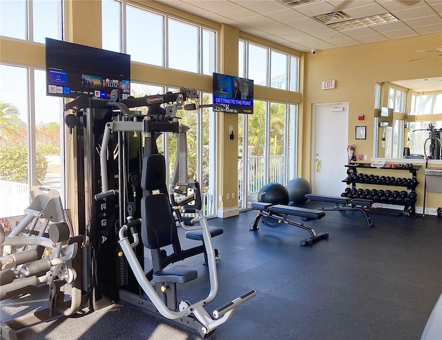 workout area featuring a paneled ceiling, a high ceiling, and visible vents